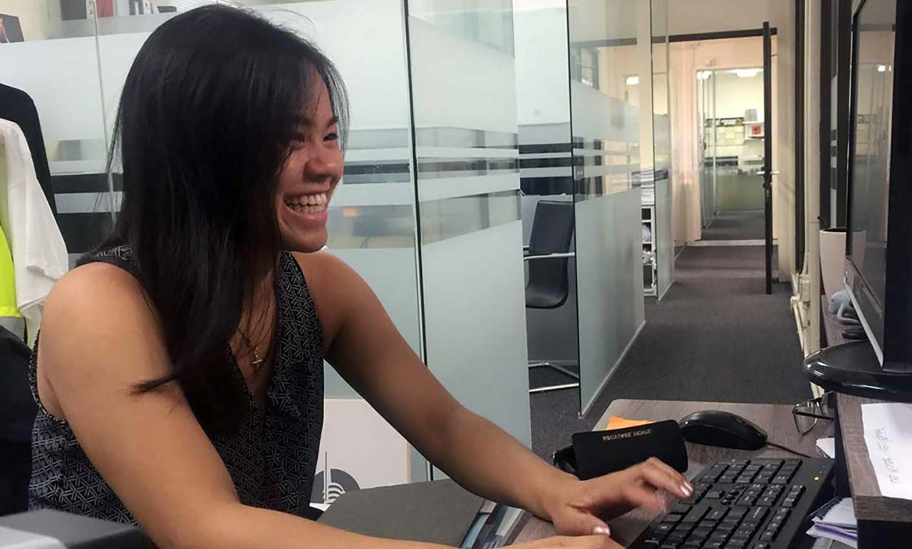 woman smiling and typing on computer keyboard